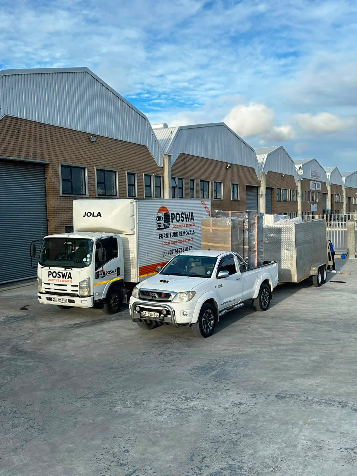 Poswa truck and bakkie with wrapped cargo outside a warehouse